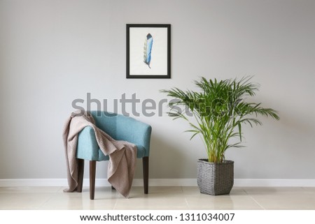 Armchair and houseplant near white wall