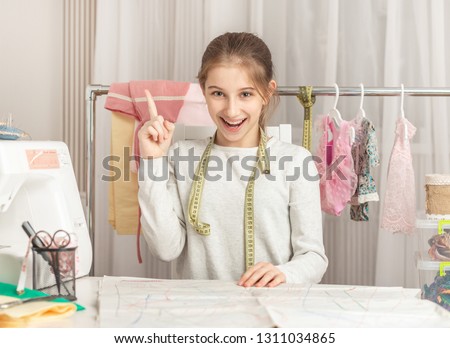 cute little girl in a sewing workshop examines pattern