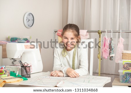 cute little girl in a sewing workshop examines pattern