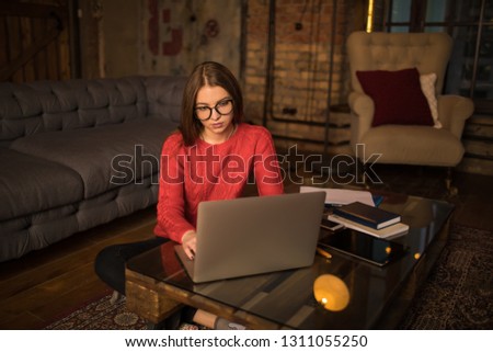 Young hipster girl smart blog writer typing article on web page via pc laptop computer, sitting at coffee table in home interior. Female university student having online learning via netbook gadget 