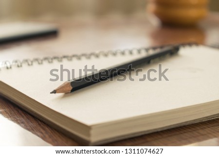 Notebook with drawings and pencil on wooden table.