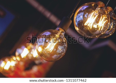 Several vintage old incandescent bulbs with a yellow spiral hanging in a row in the interior of the cafe.
