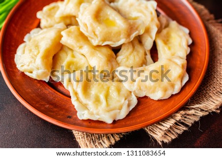 The boiled made dumplings with a stuffing with oil and green onions on a dark table. It can be used as a background