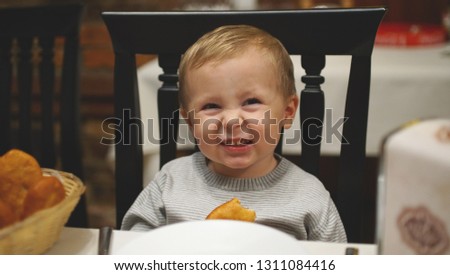 Cute little child sitting at the table on the birhday party smiling and squinting