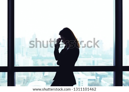 Depressed asian business woman standing at windows with city view background Royalty-Free Stock Photo #1311101462