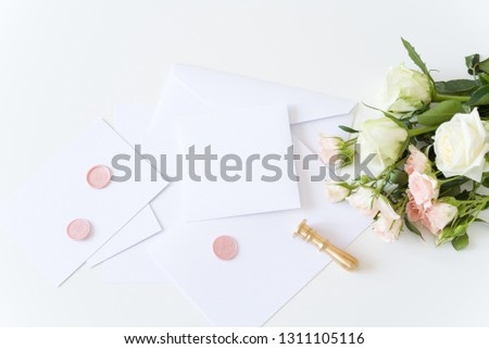Feminine stationery. White, pink flowers.Desktop. Blank greeting card, craft envelope, washi tape and golden stamp.White table background. Flat lay, top view.