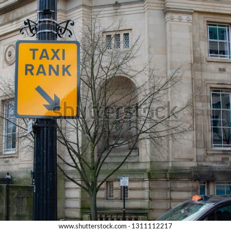 Taxi Rank Sign With Top Of Taxi Parked In Corner Of Scene