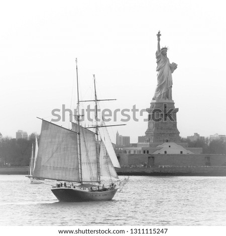 Amazing view of American symbol Statue of Liberty in New York, USA, with sailing ship and boats sailing on the Hudson River. High key black and white image.
