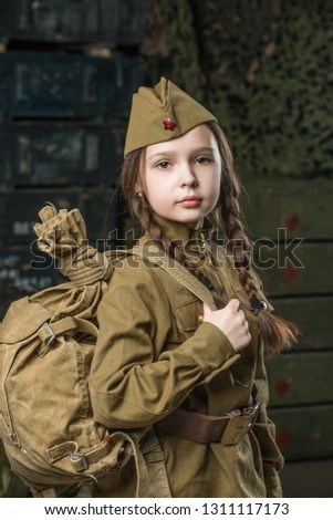 Very cute girl dressed in military uniform. She has a red star on her hat