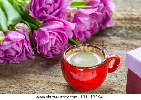 Spring flowers and coffee on a wooden background. Purple tulips