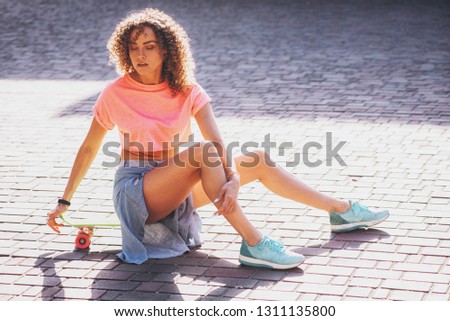 Lifestyle portrait of a young attractive woman sitting on a skateboard outdoors