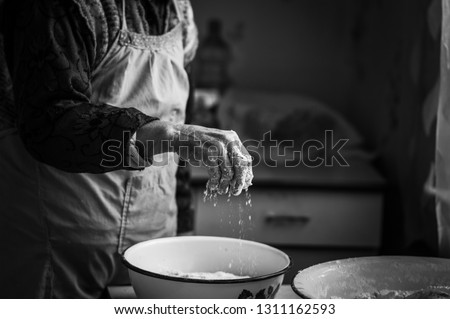 
Closeup photo of baker making dough for bread. Hands of an old woman at work with the dough. Retro look. 
Black and white photo of the hands of a woman