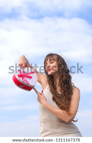A young woman is overjoyed with a decorative red 
heart gift box she has just received from her
loved one.