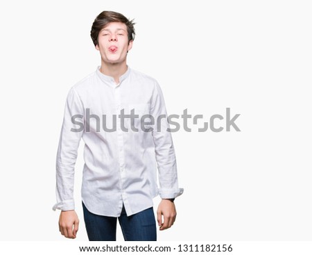 Young handsome business man over isolated background sticking tongue out happy with funny expression. Emotion concept.