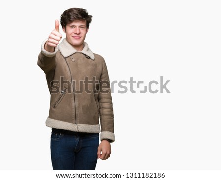 Young handsome man wearing winter coat over isolated background showing and pointing up with finger number one while smiling confident and happy.