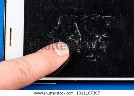 index finger on the cracked dark screen of a smartphone close-up concept of repair and gadgets