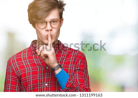 Young handsome man wearing glasses over isolated background asking to be quiet with finger on lips. Silence and secret concept.