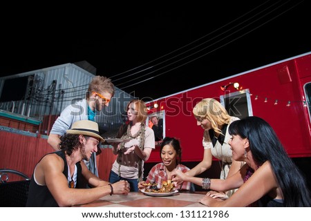 Friends talking and eating pizza near Food Truck