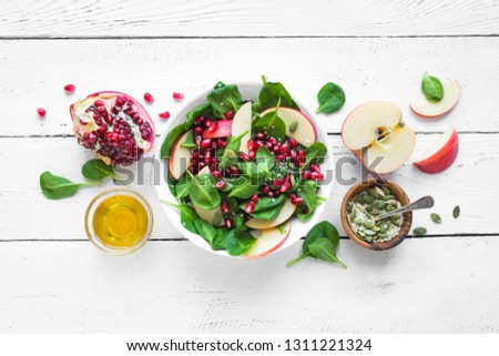 Homemade spinach, apple salad with pomegranate seeds on white wooden background, copy space. Heathy clean vegan raw food, fresh salad and ingredients. Royalty-Free Stock Photo #1311221324