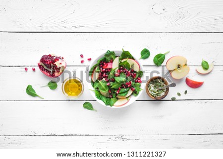 Homemade spinach, apple salad with pomegranate seeds on white wooden background, copy space. Heathy clean vegan raw food, fresh salad and ingredients. Royalty-Free Stock Photo #1311221327