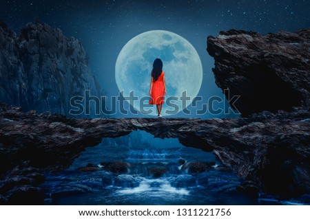 The little girl stood on a stone bridge looking at the full moon beautifully.