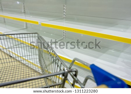 Empty shelves in the store. Copy space. Template for design. Concept of sales or shopping background. Food basket near empty showcases without products in the supermarket.