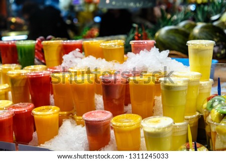 Fresh juice from fruits and vegetables in plastic cups covered with ice