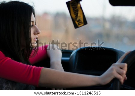 Young beautiful woman holding the wheel. Hangs a badge of warning. Woman driver.