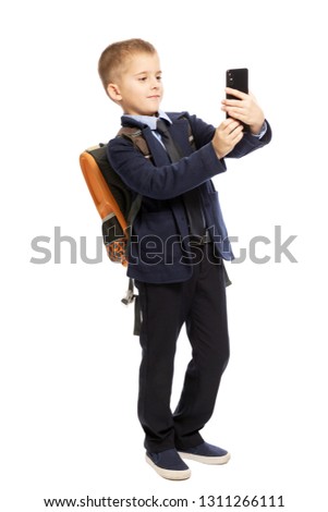 Schoolboy makes selfie on the phone, isolated on white background