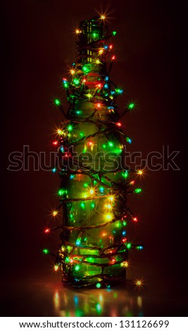 garland on green bottle on dark red background. similar to christmas fir-tree.