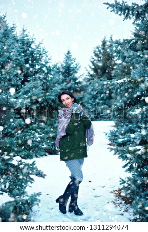 beautiful woman is in winter forest, green fir trees with snow