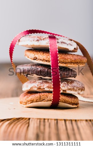 A few gingerbread cookies wrapped in red ribbon Happy Christmas on wooden table. Plain background. Portrait orientation