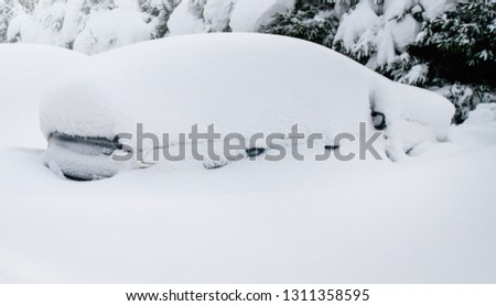 Cars covered with heavy white snow on calamity road. Winter car concept in storm or blizzard.