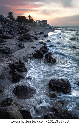 Waves along the beach of Chelem after sunset with orange sky, Mexico