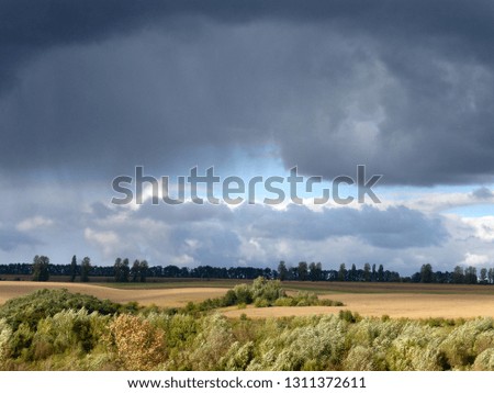 String of thunderclouds over rural meadows