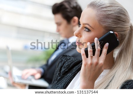 Close up portrait of attractive businesswoman talking on smart phone at meeting.