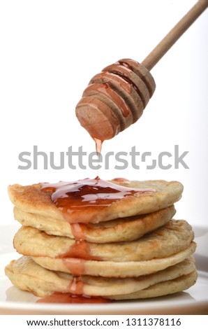Pouring a stack of oatmeal with strawberry jam with a spindle. White background