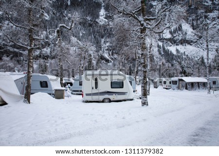 Caravan in the snow. Caravan on a campsite in the winter time. Winter vacations in the mountains. Family holiday with a camping car in Europe. Frozen temperature in the great outdoors.