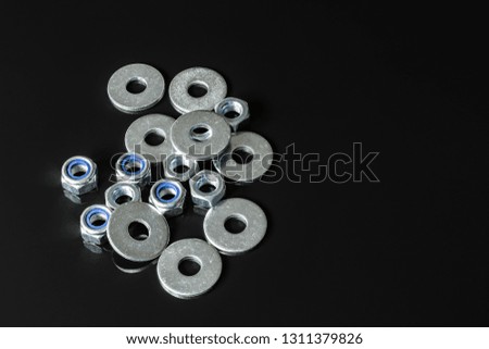 Metal screws, washers, nuts and keys on a black mirror background. Great contrast image
