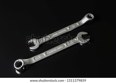 Metal screws, washers, nuts and keys on a black mirror background. Great contrast image
