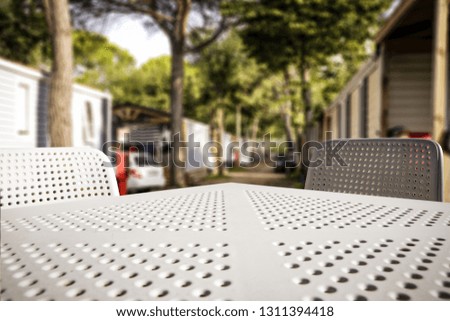 White table of free space with two chairs. Empty space for your product. Blurred background of camping and summer time in Italy. 