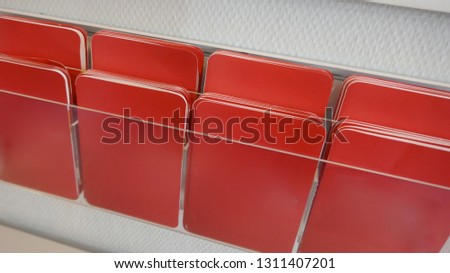 Many red unlabeled sticky notes on a shelf
