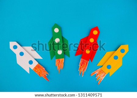 top view of flying multi-colored rockets from paper on a blue background