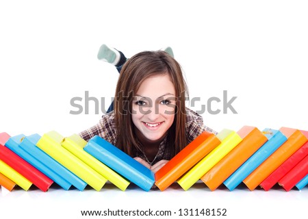Picture of a happy teenage girl lying on the floor behind a row of colorful books.