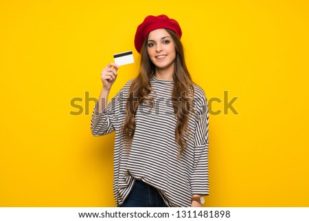 Girl with french style over yellow wall making a selfie