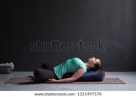 Woman practicing yoga concept, lying in Reclined Butterfly exercise Royalty-Free Stock Photo #1311497570