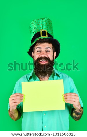 Saint Patrick's Day. Bearded man in green top hat holds green board. St Patrick's Day. Happy four leafed clover. Green hat with clover. Ireland tradition. Copy space. Sale. Discount. Advertising.