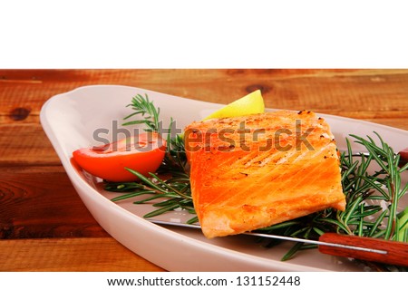 healthy food: hot baked salmon piece served over glass plate on wood