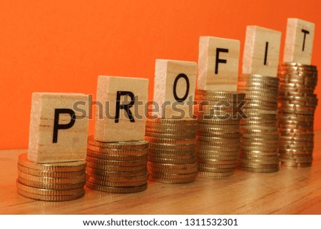 Business concept with PROFIT word on wooden plate onto hike trend stacked of coins.