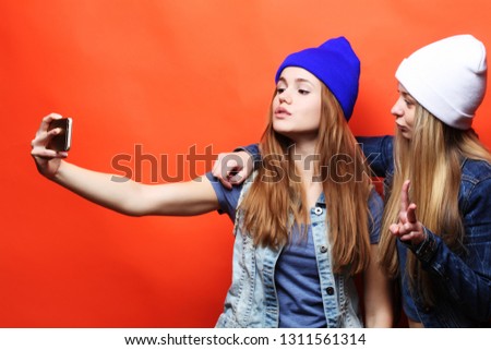 lifestyle, emotion, tehnology  and people concept: two young hipster girls friends  taking selfie 